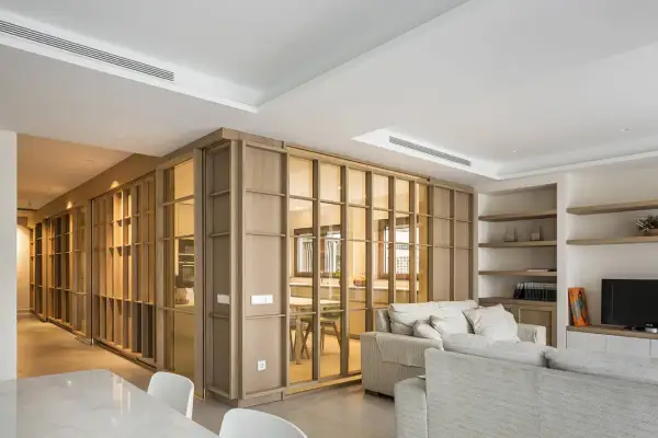 Un espacio moderno y luminoso, ideal para diseñar interiores. Muebles de madera y cristal separan ambientes, creando un hogar acogedor.